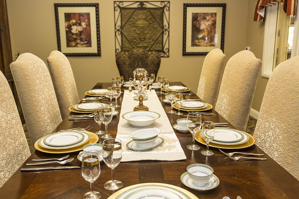 A formal dining table set with elegant plates and glassware, prepared for a sophisticated dinner.