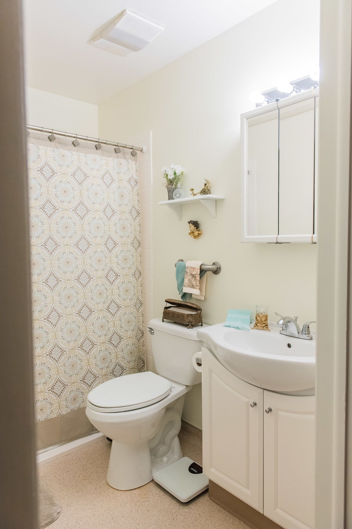 A neatly organized bathroom with a patterned shower curtain and white fixtures.