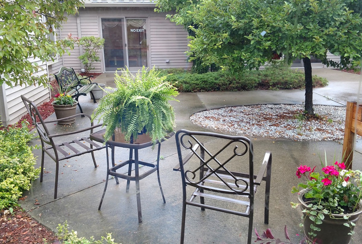A peaceful patio setting featuring outdoor furniture and lush greenery.