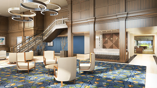 A stylish hotel lobby featuring modern furniture, a staircase, and elegant lighting.