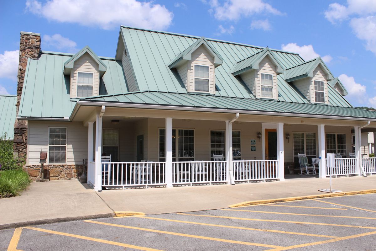 A quaint building with a green metal roof and a welcoming porch.