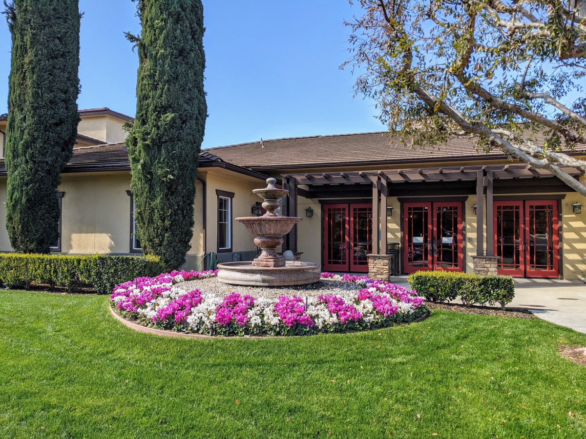A beautifully landscaped area in front of a building featuring a circular flower bed surrounding a central fountain.