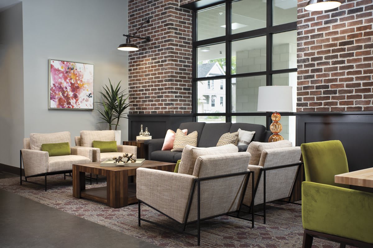 A modern living room with comfortable seating, featuring neutral tones and a brick accent wall.