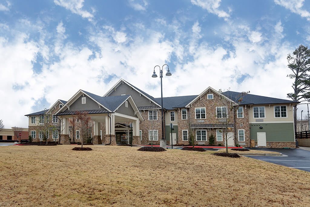 A modern residential building with landscaped surroundings under a blue sky.