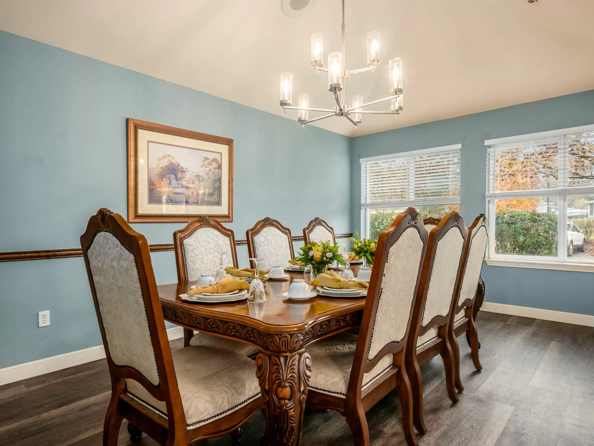 Elegant dining room with a large wooden table, upholstered chairs, and a modern chandelier.