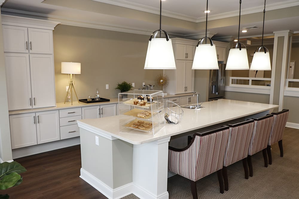 A modern kitchen featuring a large island with pendant lighting and bar stools, surrounded by stylish cabinetry and appliances.