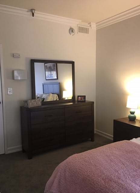 A cozy bedroom with a dresser, mirror, and lamp.
