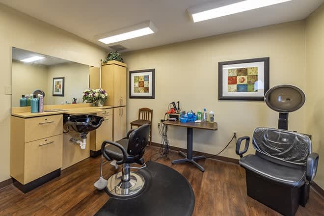 A cozy hair salon interior with chairs, mirrors, and artwork on the walls.