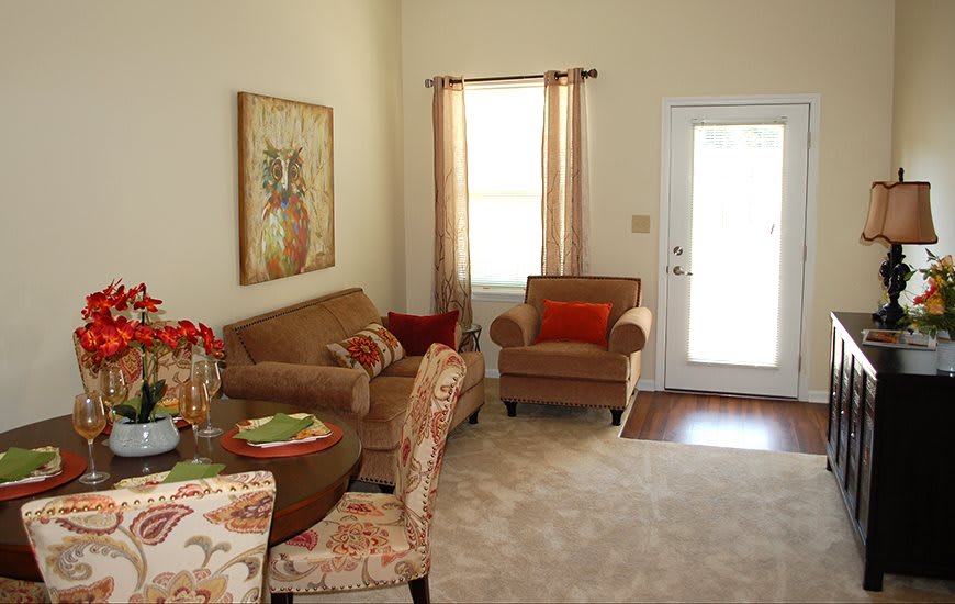 A cozy living room with a sofa, armchair, and dining table set in a well-lit space.