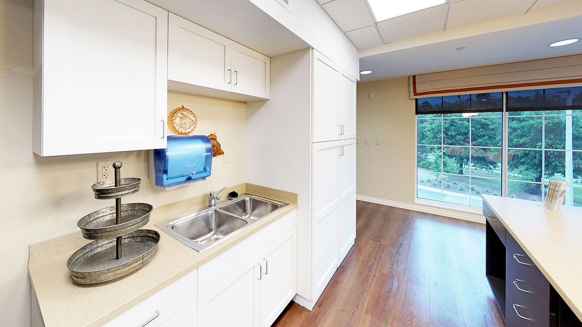 A clean kitchen area with white cabinets, a double sink, and hardwood flooring.