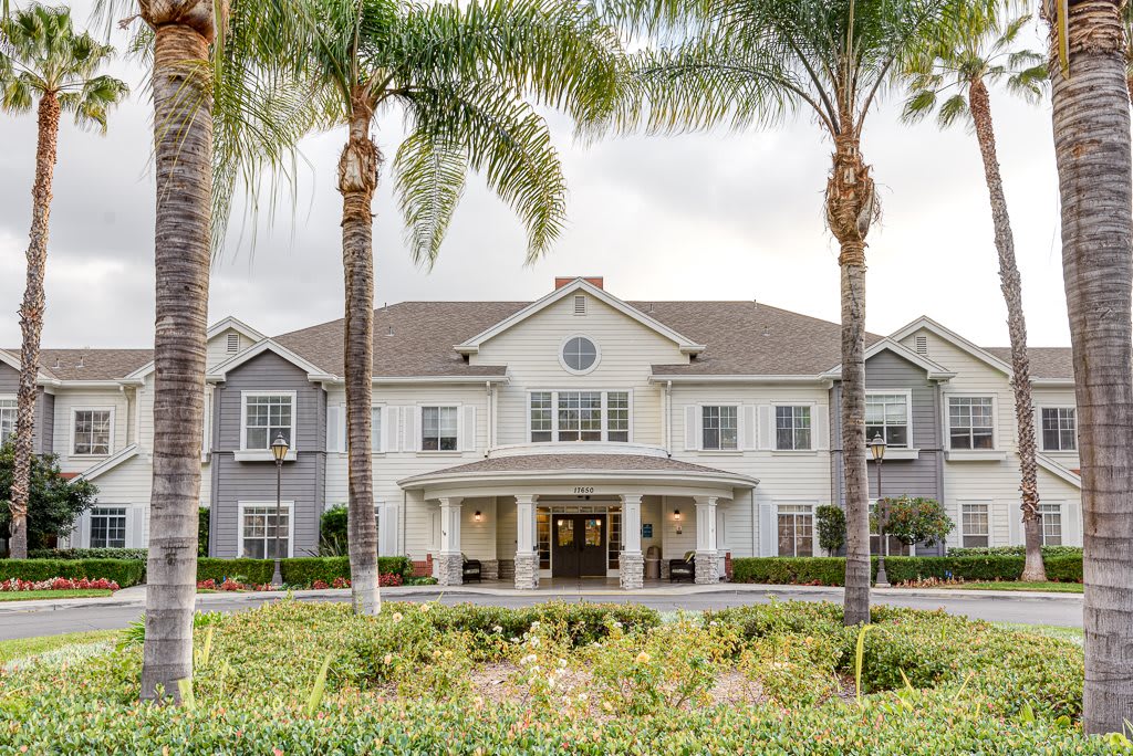 A white residential building with palm trees in front.