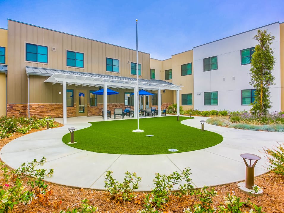 A modern building with a well-maintained courtyard featuring a circular lawn and landscaping.
