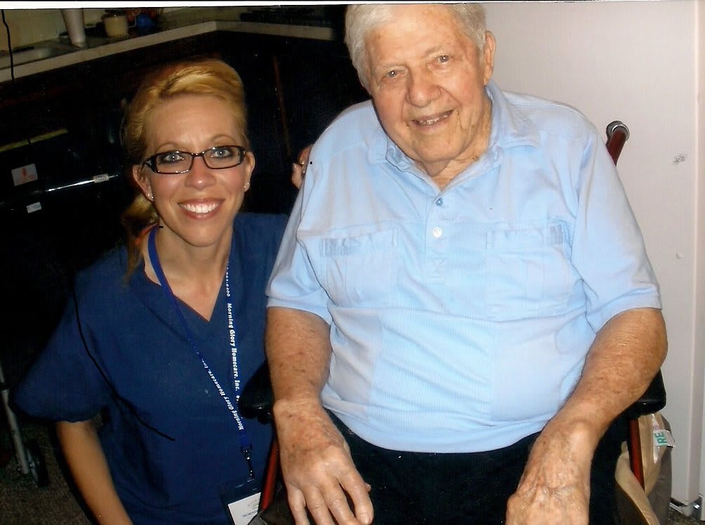 An elderly man smiling with a nurse by his side.