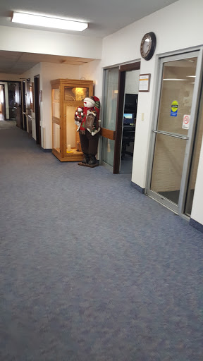 A clown statue standing in a hallway, next to an office entrance.