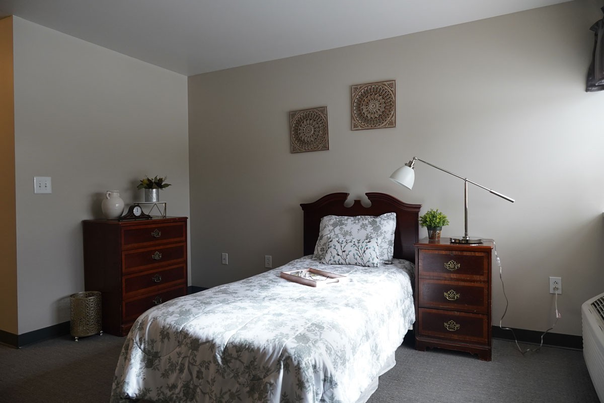 A cozy bedroom with a single bed, wooden furniture, and decorative elements.