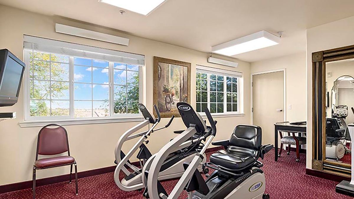A well-lit fitness center featuring recumbent bikes next to large windows.