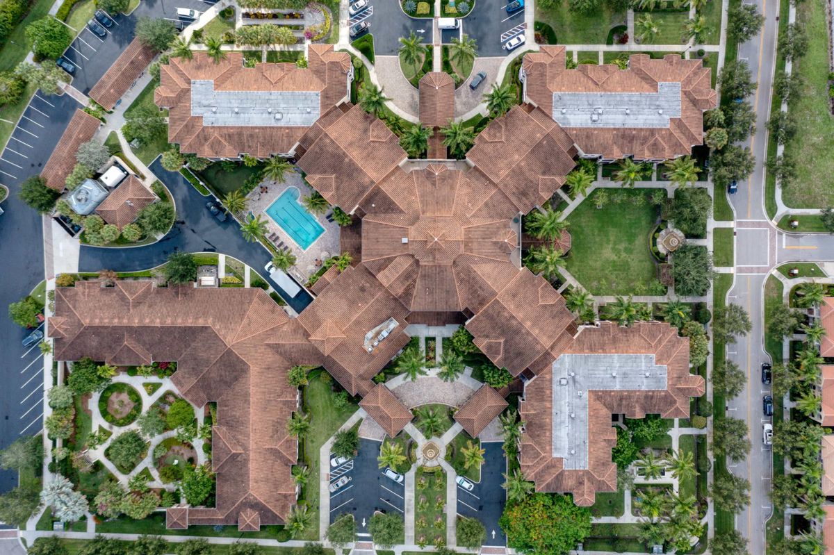 Aerial view of a large, symmetrical building complex with gardens and a swimming pool.