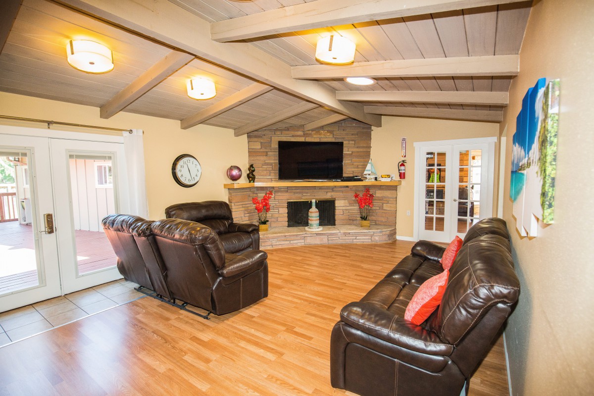 A cozy living room with leather sofas, a wall-mounted TV, and a decorative fireplace.