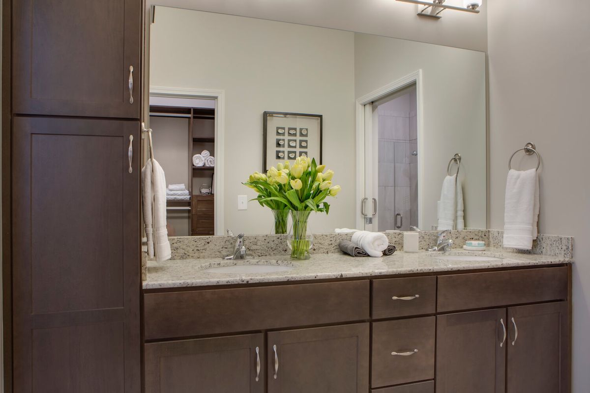 A well-organized bathroom vanity with flowers and towels on the countertop.