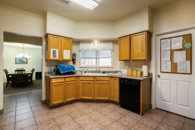 A kitchen interior featuring wooden cabinets, a sink, and tiled flooring.