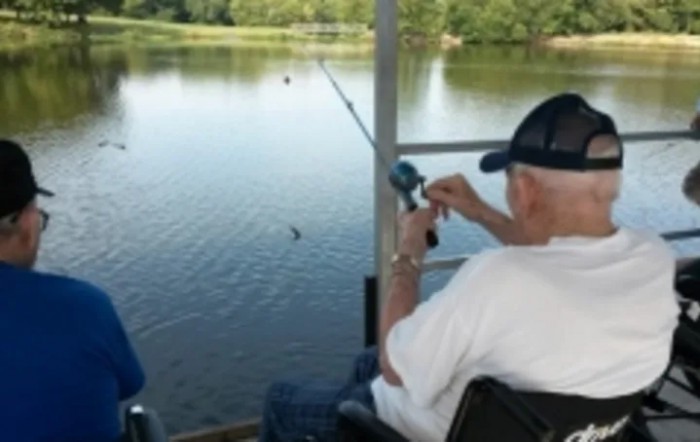 A person fishing by a lake on a sunny day.