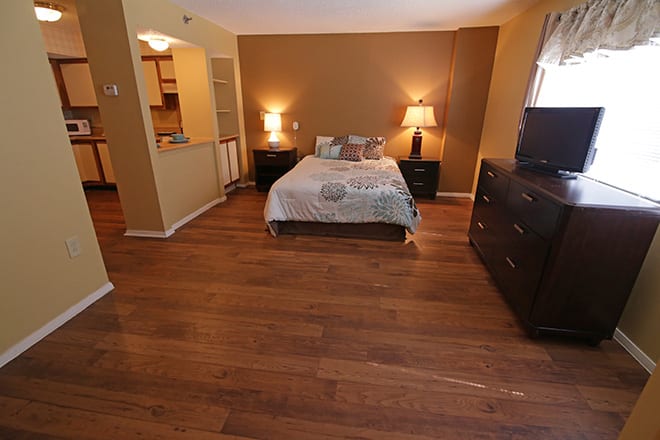 A cozy bedroom with wood flooring and warm lighting.