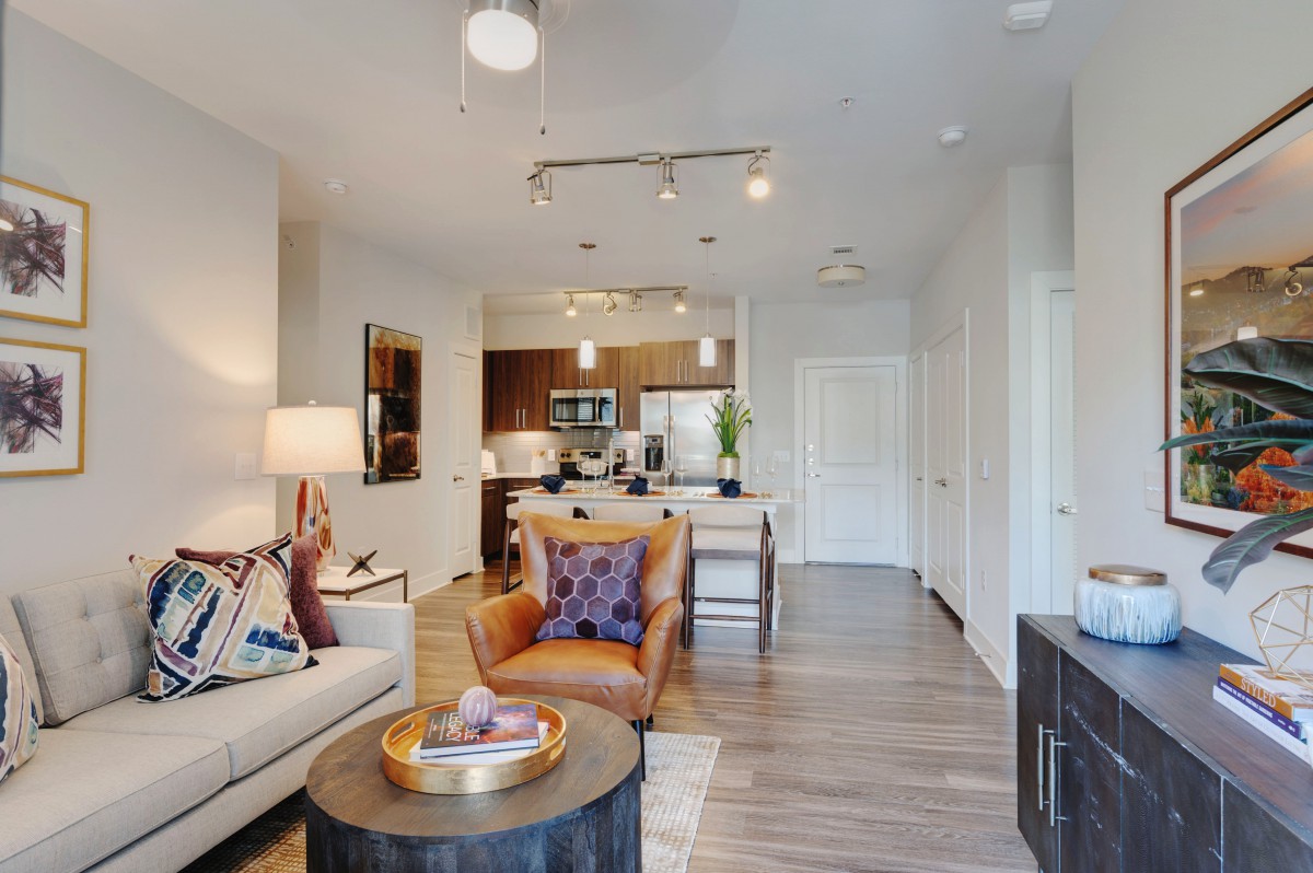 A modern open-concept living room and kitchen area with stylish decor and wood flooring.