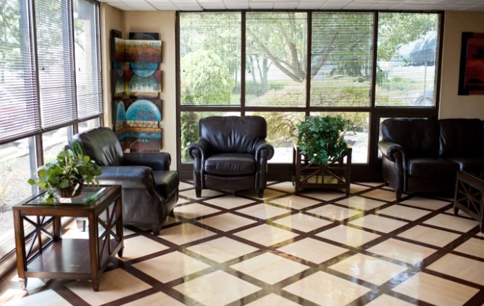 A cozy waiting room with leather armchairs, natural light, and indoor plants.