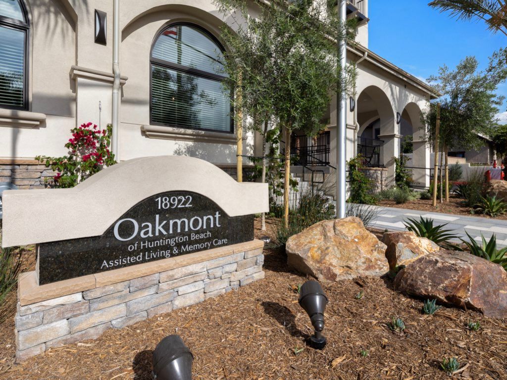 Entrance of a building with a prominent sign and landscaped surroundings.