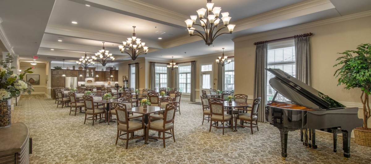 A spacious dining room with elegant chandeliers and neatly arranged tables and chairs.