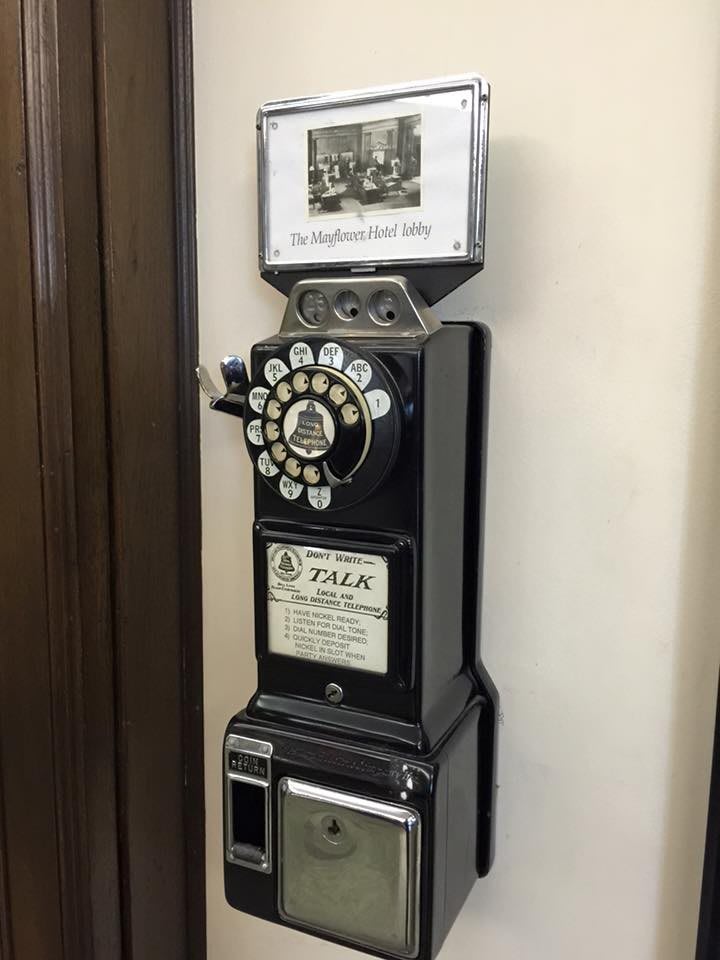 A vintage rotary payphone mounted on a wall.