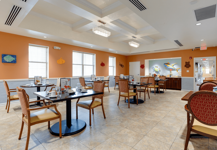 An empty dining room with neatly arranged tables and chairs, featuring bright lighting and a warm color palette.