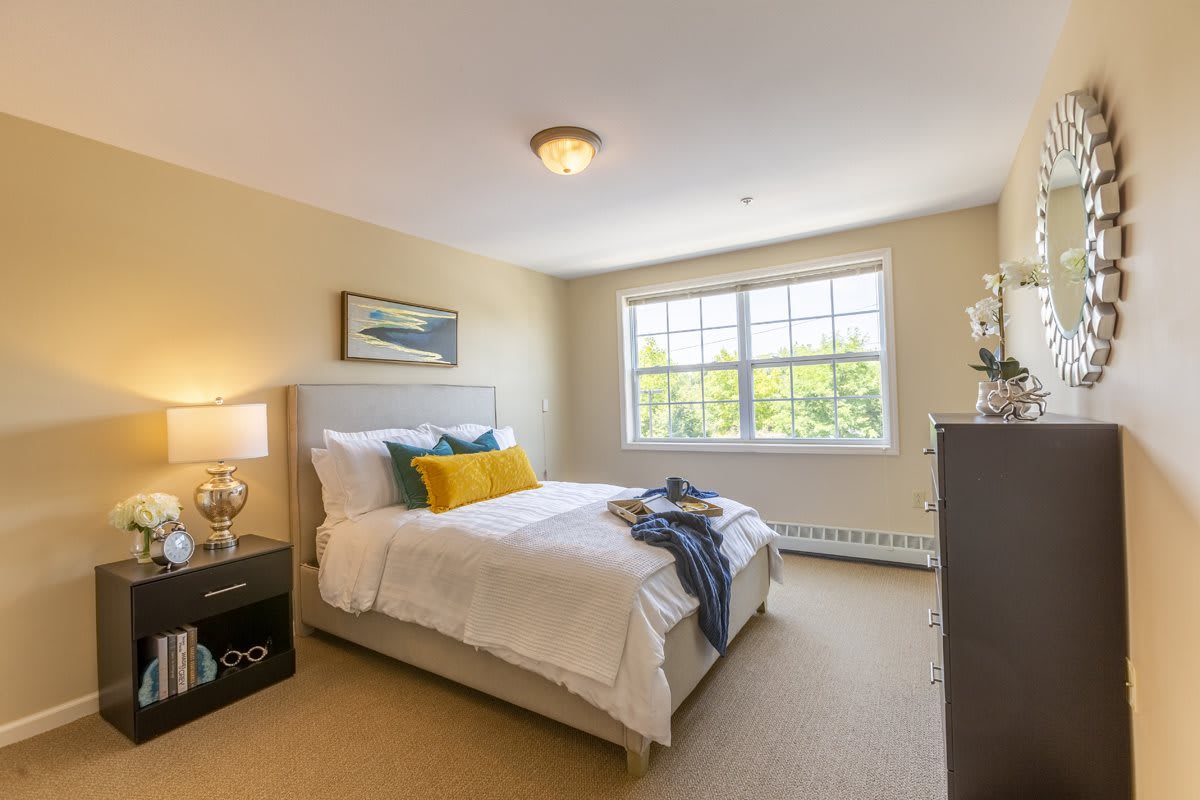 A cozy bedroom with a large window and neatly arranged decor.