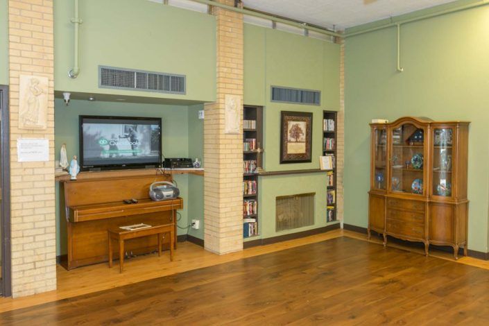 A cozy living room with a TV, bookshelf, and wooden cabinet on hardwood flooring.