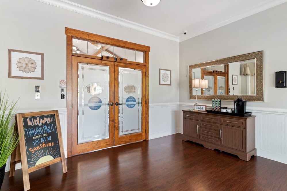A welcoming entrance with wooden doors, a mirror on the wall, and a chalkboard on display.