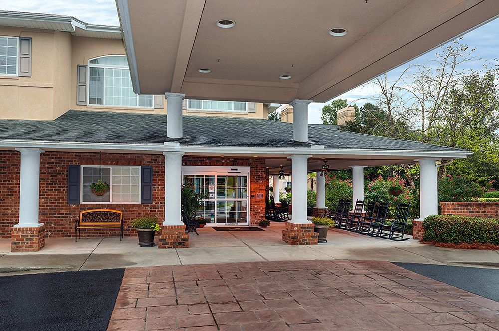 The entrance of a building with a covered canopy and potted plants lining the walkway.