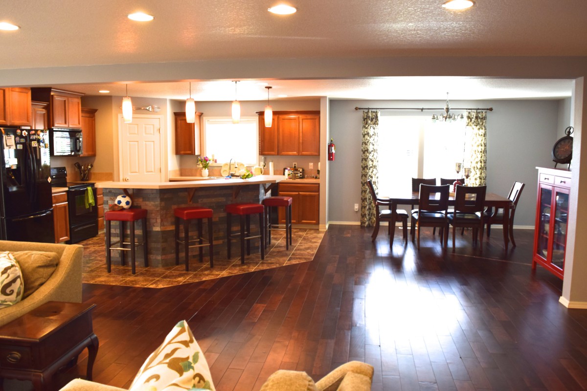 A modern open floor plan featuring a kitchen with bar stools and a connected dining area.