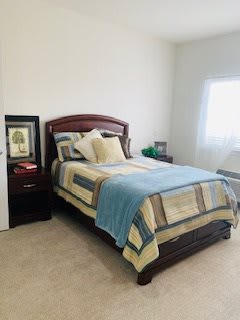 A neatly arranged bedroom with a bed, nightstand, and decor.