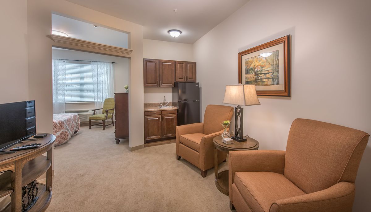 A cozy living room with comfortable chairs and a small kitchenette.