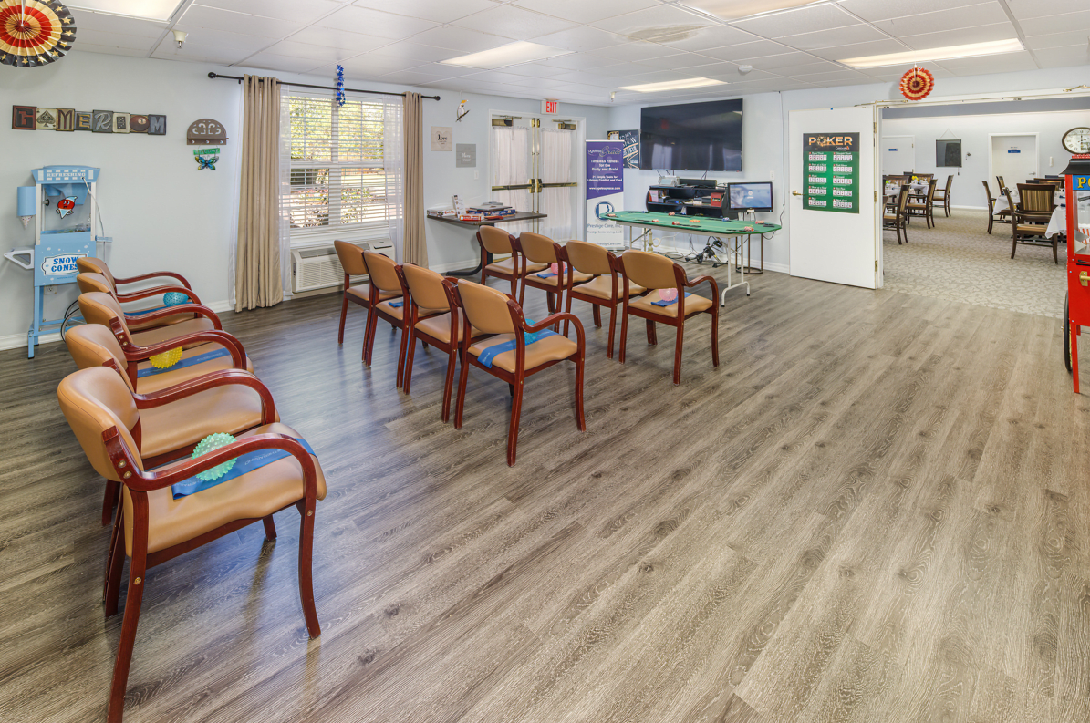 A spacious waiting room with lined-up chairs, wooden flooring, and a large television.