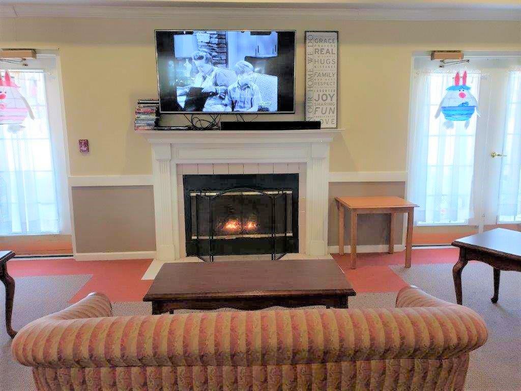 A cozy living room with a fireplace and television, complemented by a comfortable sofa and coffee table.