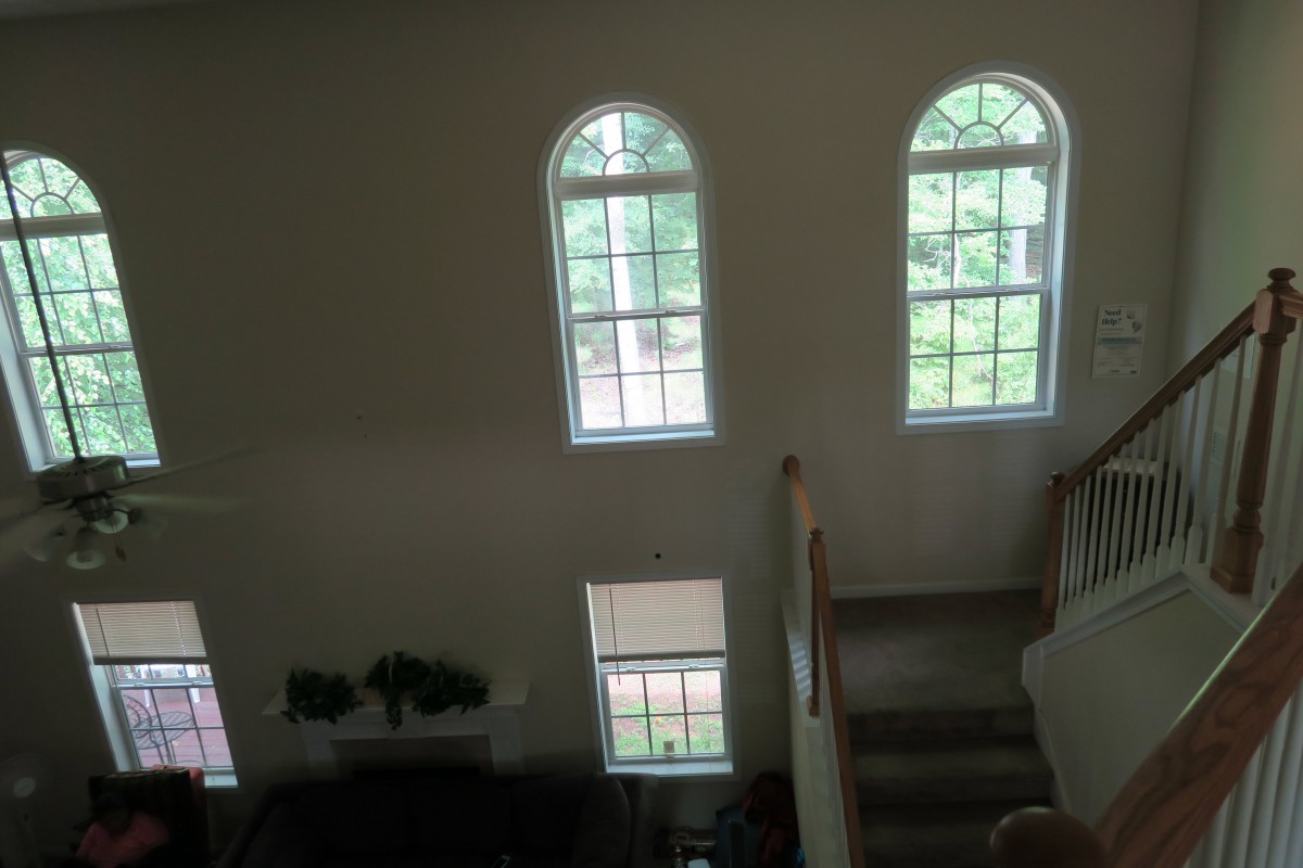 A view of a living room with large arched windows and a staircase.