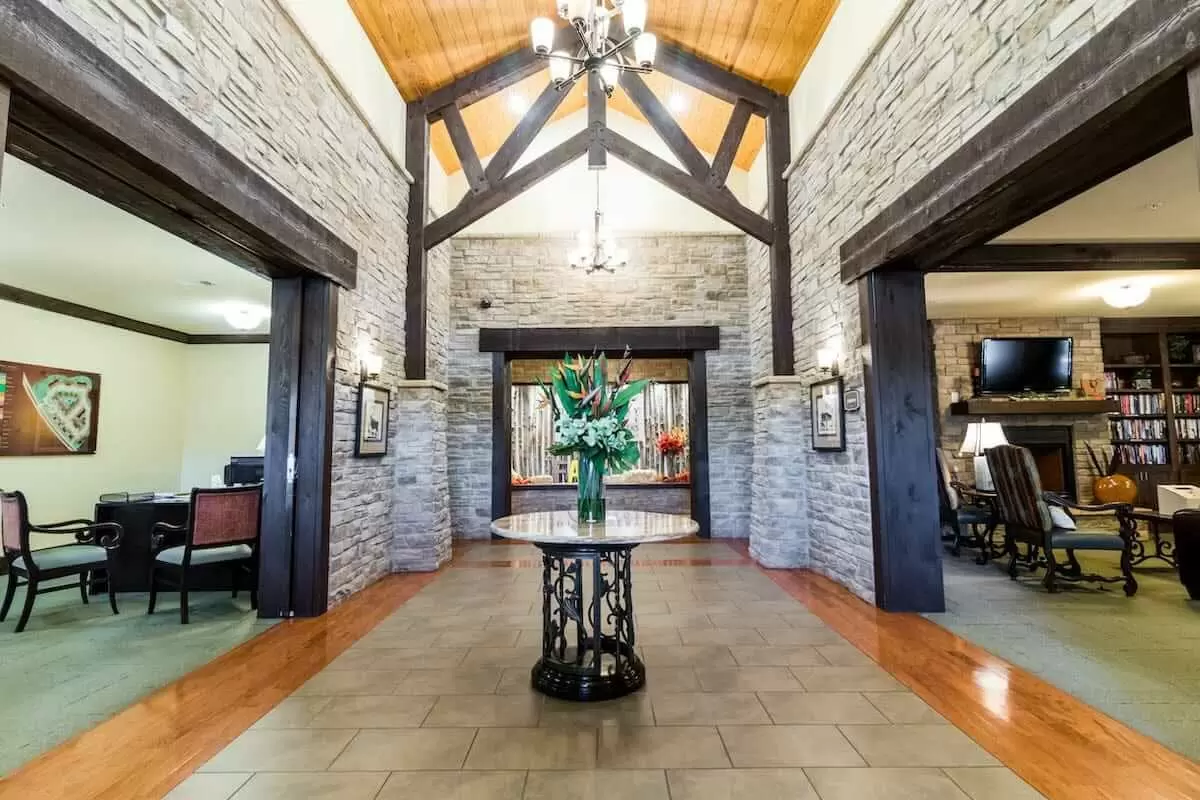A spacious lobby with stone walls, a vaulted ceiling, and a central table adorned with flowers.