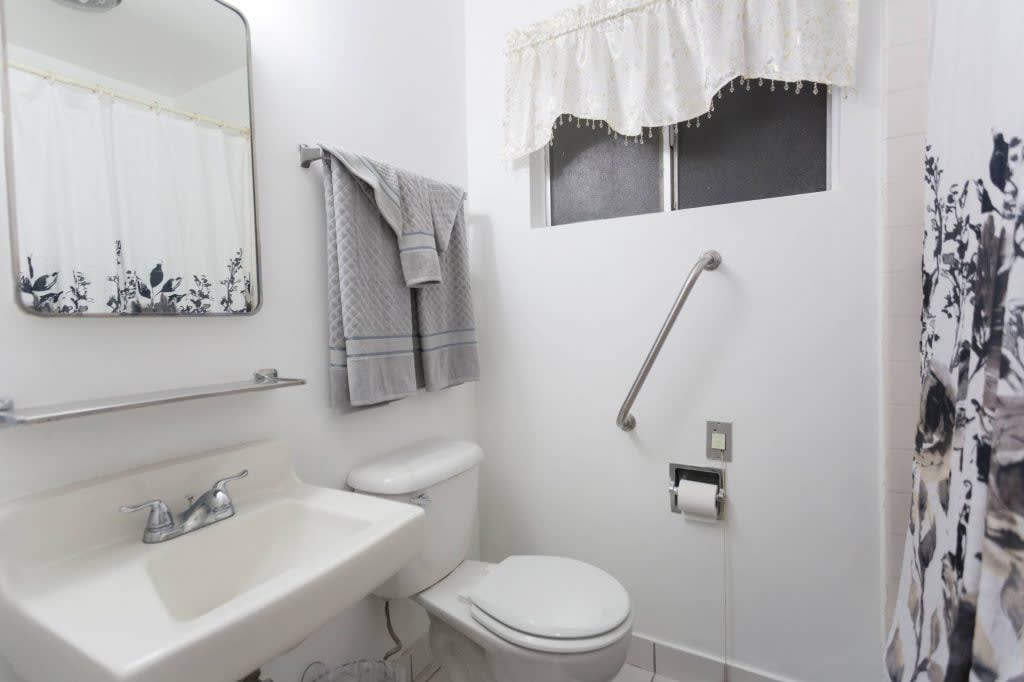 A clean and simple bathroom with a toilet, sink, and a grab bar for accessibility.
