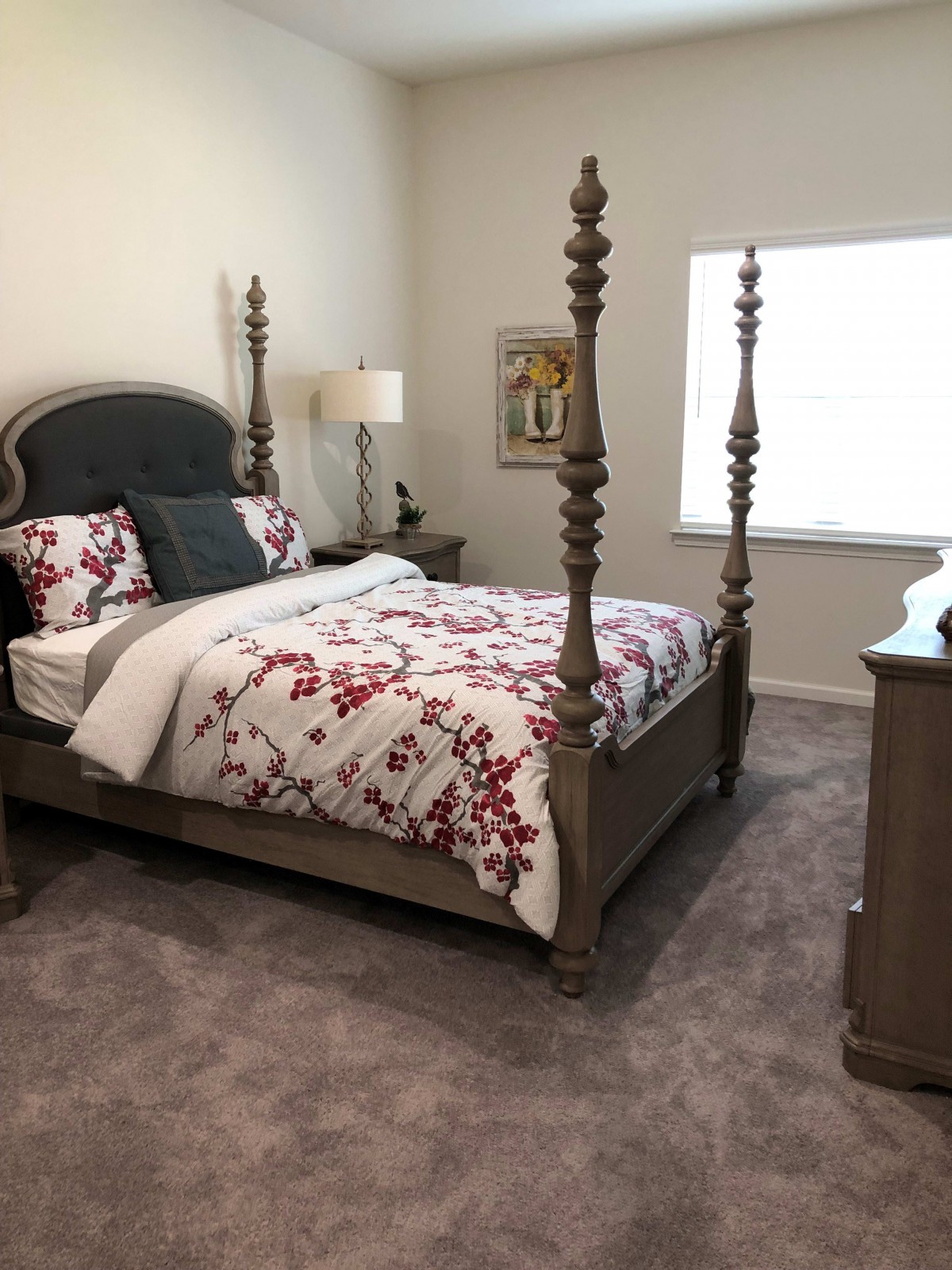 A cozy bedroom with a four-poster bed, floral bedding, and elegant furniture.
