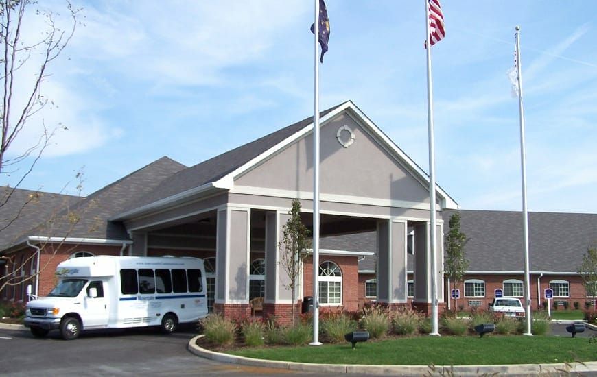 A building entrance with flags and a parked shuttle bus in front.