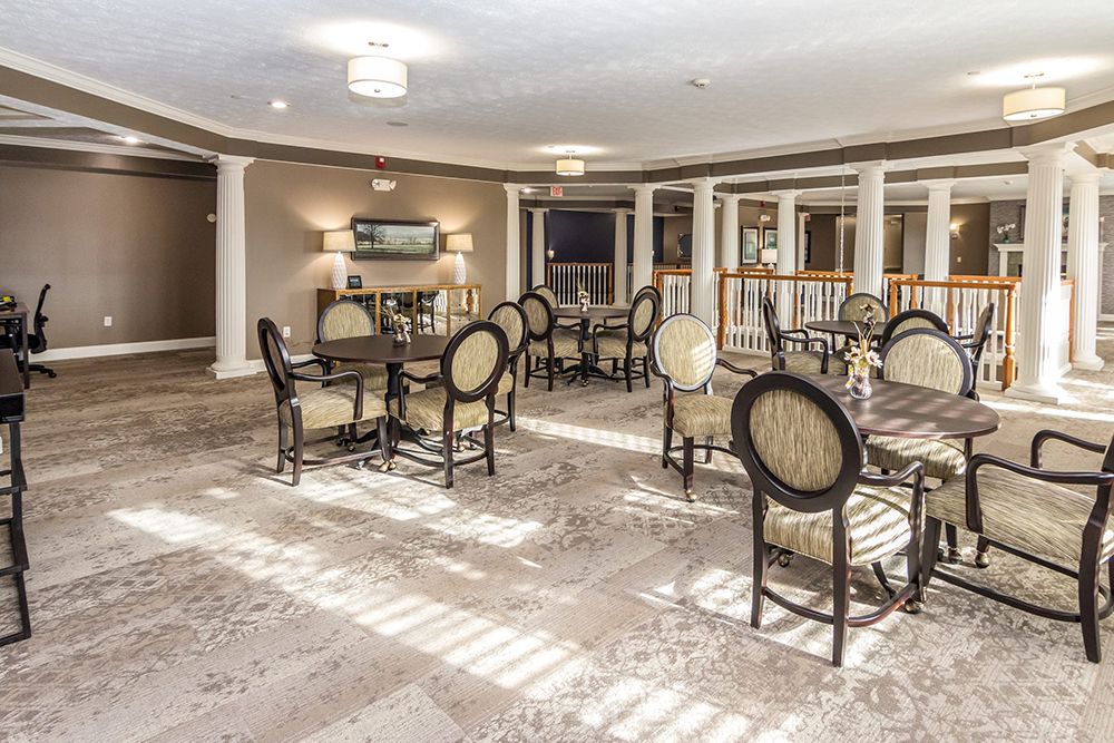 A well-lit dining area with several tables and chairs arranged on a carpeted floor.