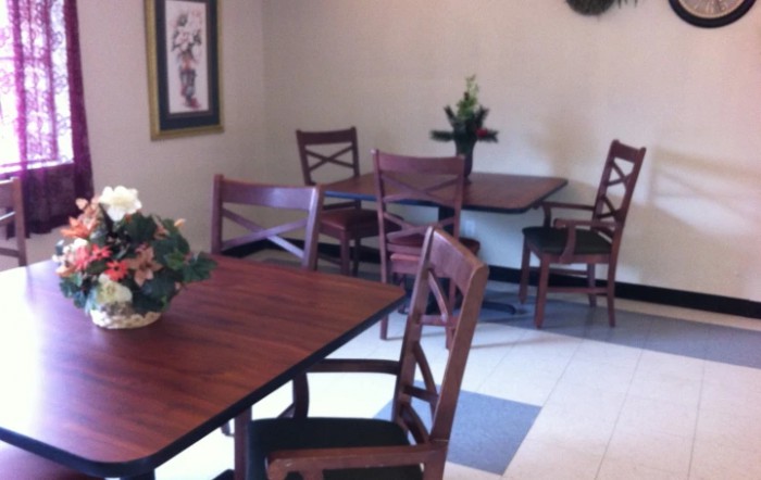 A cozy dining area with wooden tables and chairs, decorated with plants.