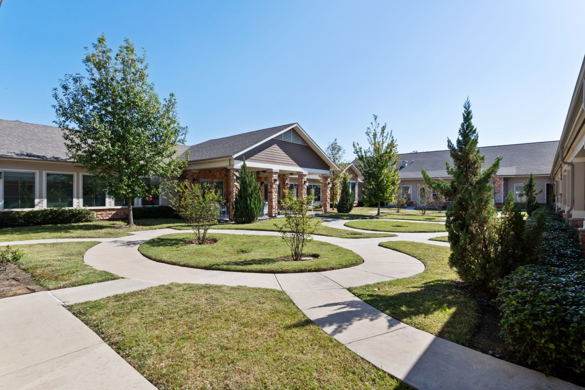 A suburban house with a landscaped yard and winding pathways on a sunny day.