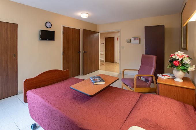 A cozy hotel room featuring a bed, chair, and wall-mounted television.